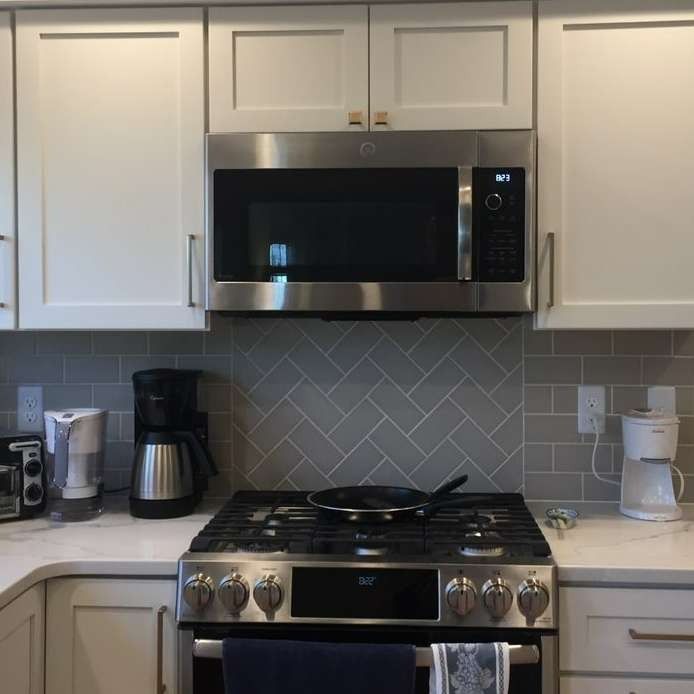 Modern kitchen with white cabinets, stainless steel microwave, gas stove, and countertop appliances.