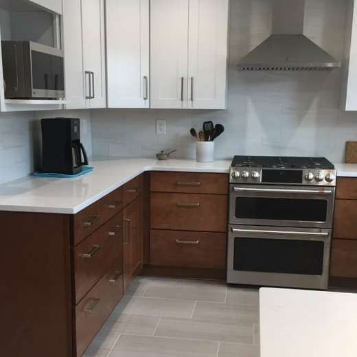 Modern kitchen with white cabinets, brown lower cabinets, stainless steel stove, and gray tile flooring