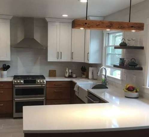 Modern kitchen with white cabinets, stainless stove, wood island, and large pendant light