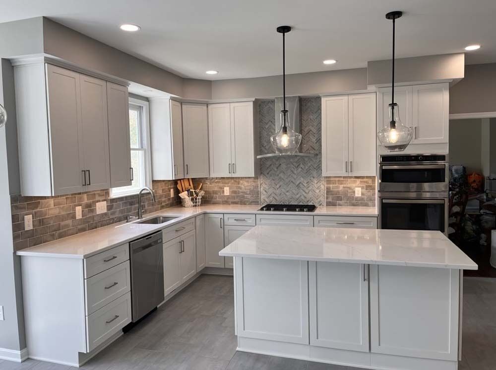 Modern white kitchen with island, gray cabinets, mosaic backsplash, and pendant lights