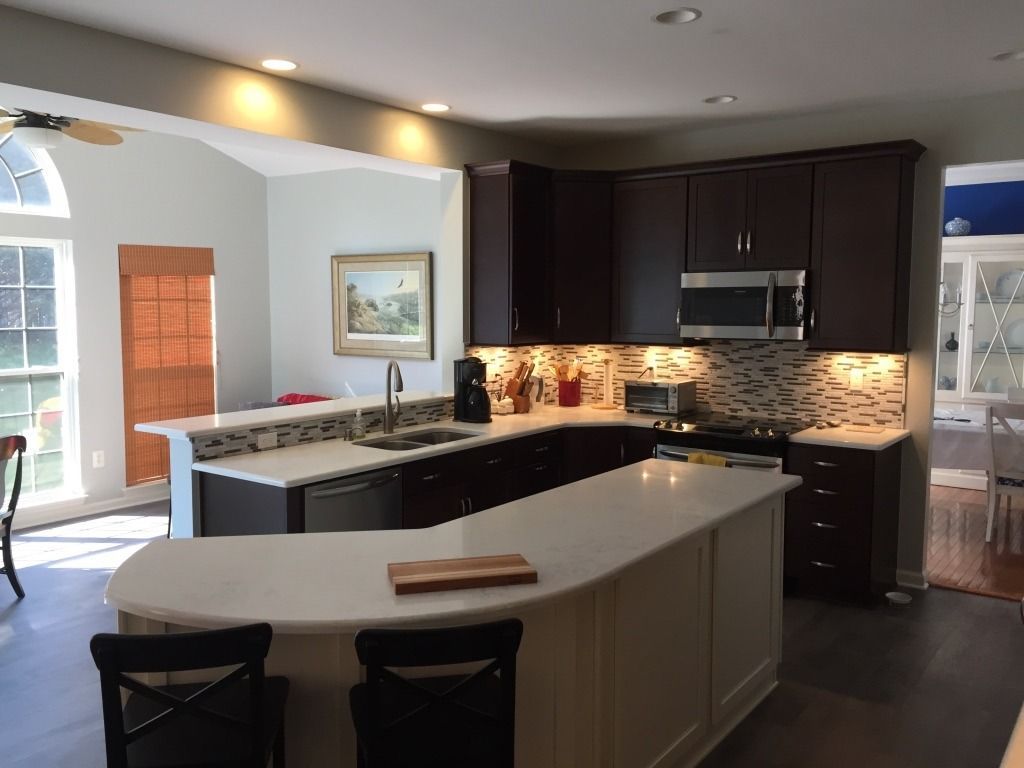 Modern kitchen with dark cabinets, granite countertops, island seating, and warm recessed lighting