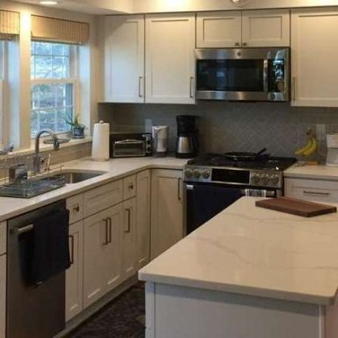 Modern kitchen with white cabinets, stainless steel appliances, island, sink, and window over the counter