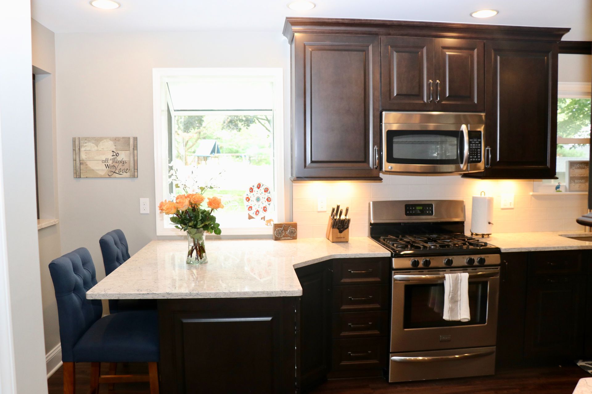 Modern kitchen with dark wood cabinets, stainless appliances, white island, and blue barstools