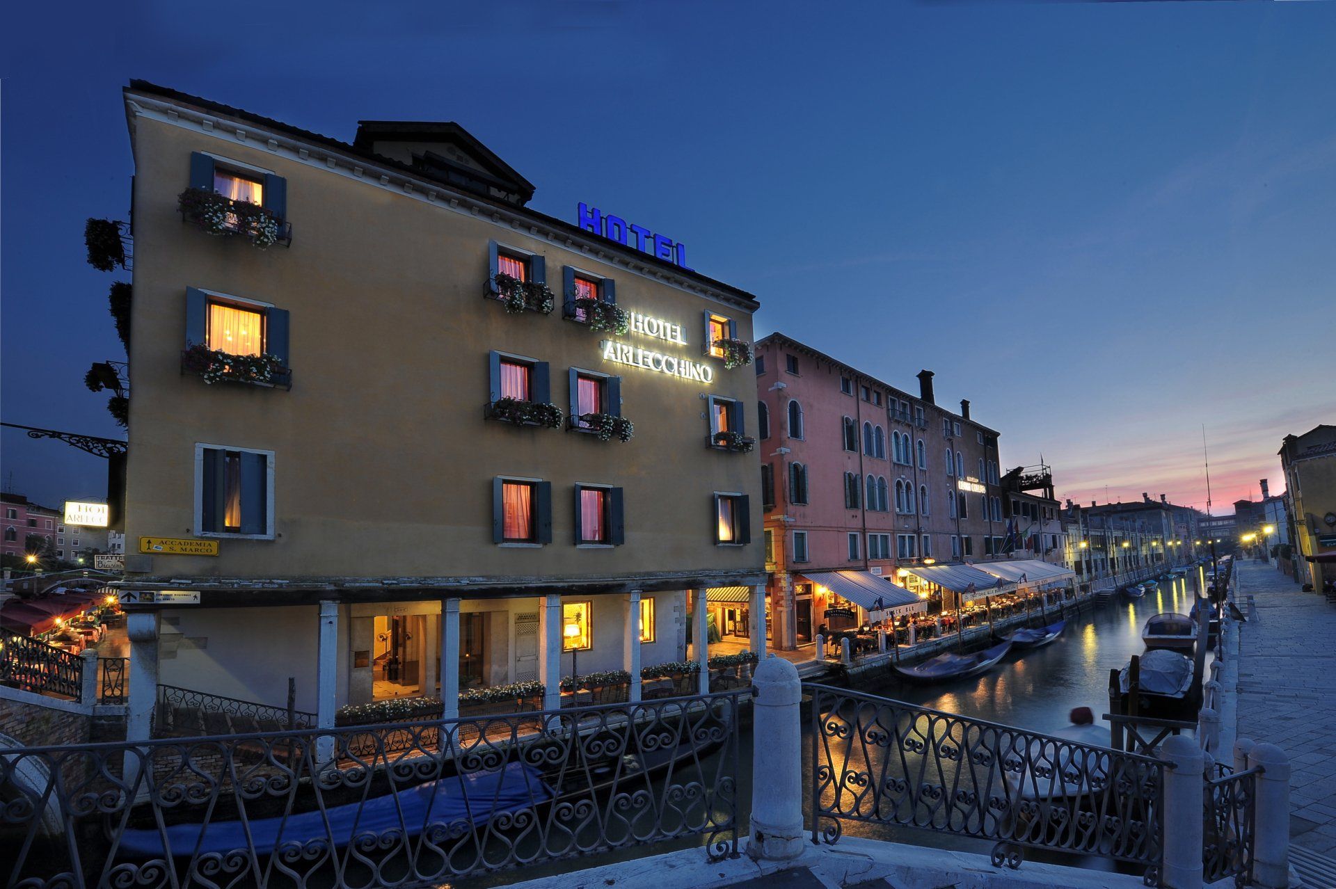 Canal-side hotel at dusk with lit windows and reflections on the water