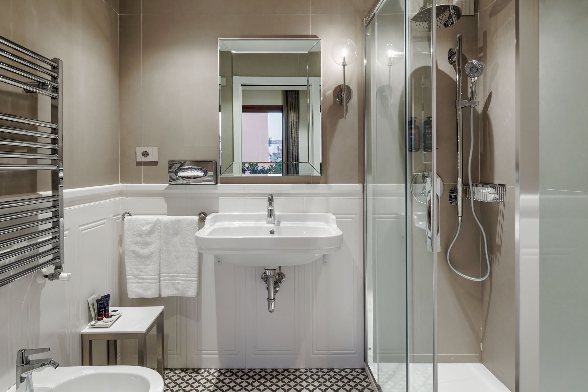 Modern bathroom with sink, mirror, glass shower, towel rack, and black-and-white floor tiles