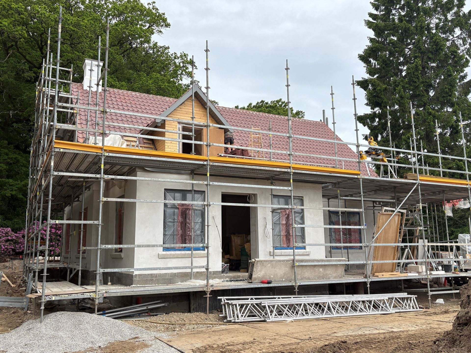 Hus under opførelse med stillads og delvist færdiggjort tag og vægge
