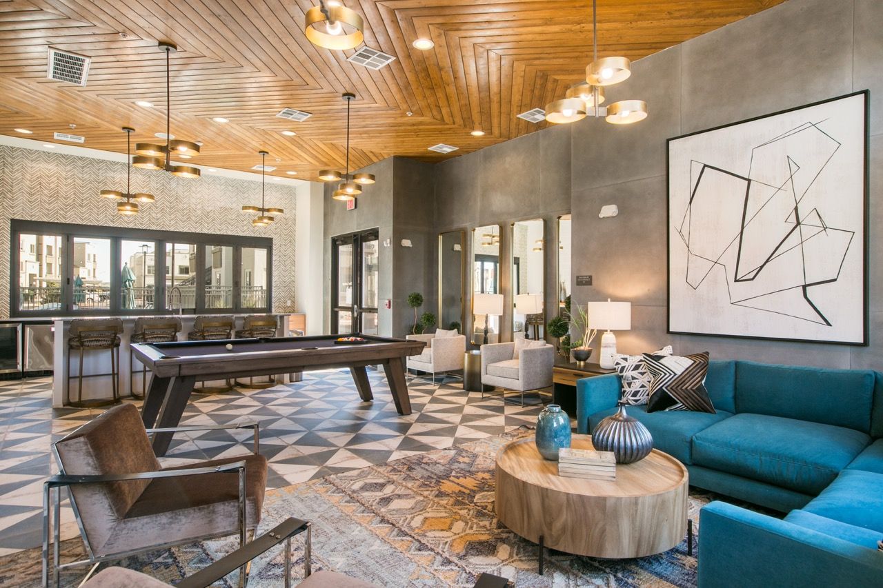 Modern resident lounge with a pool table, teal sofa, and geometric art.