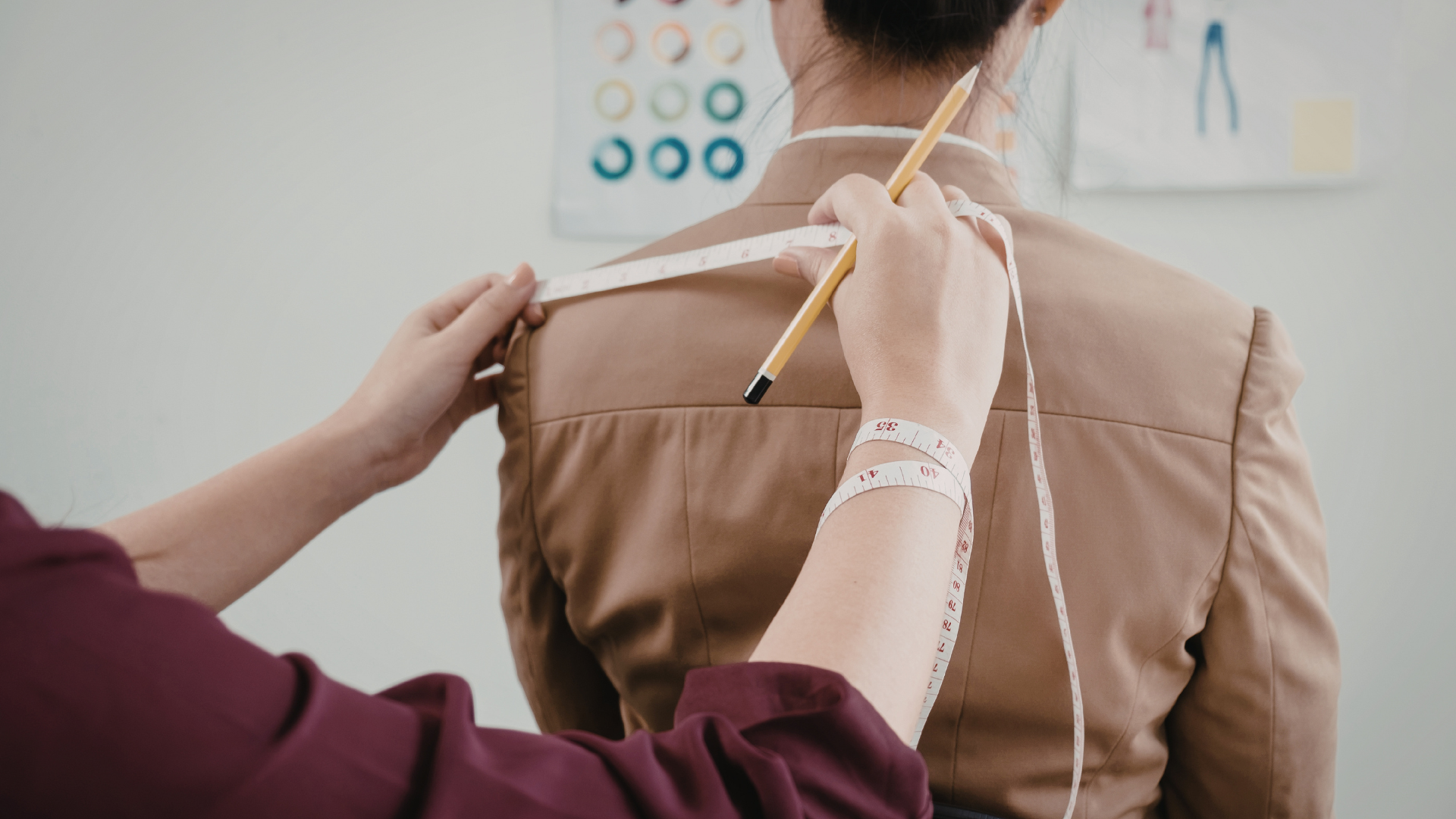 Tailor marking shoulder measurements on a brown jacket with a chalk pencil