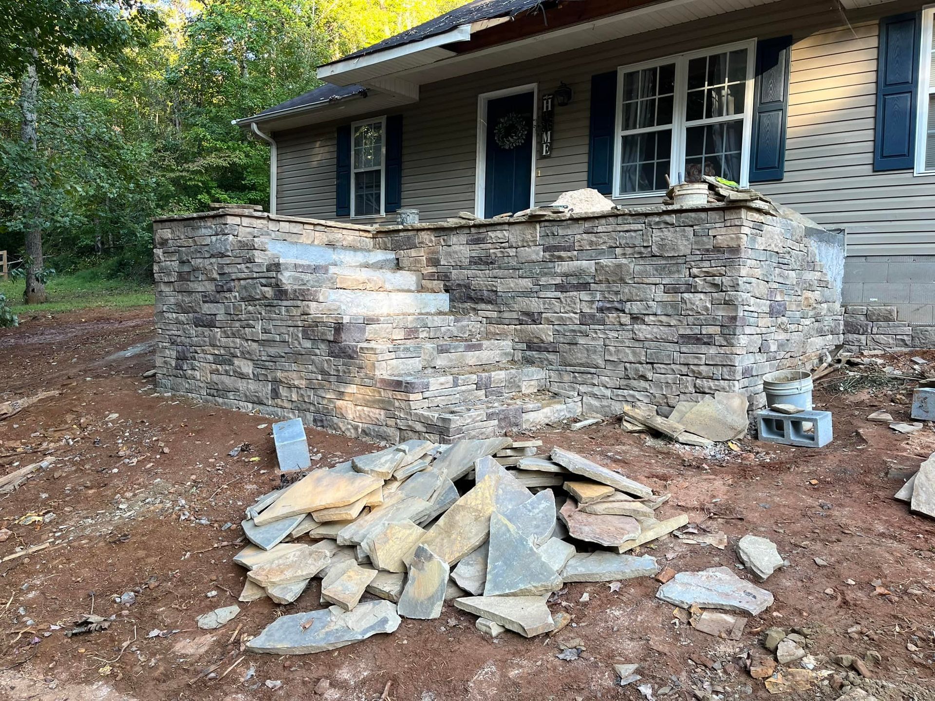 concrete work murrayville ga Partially built stone porch wall with debris piled in front of a house in a wooded yard