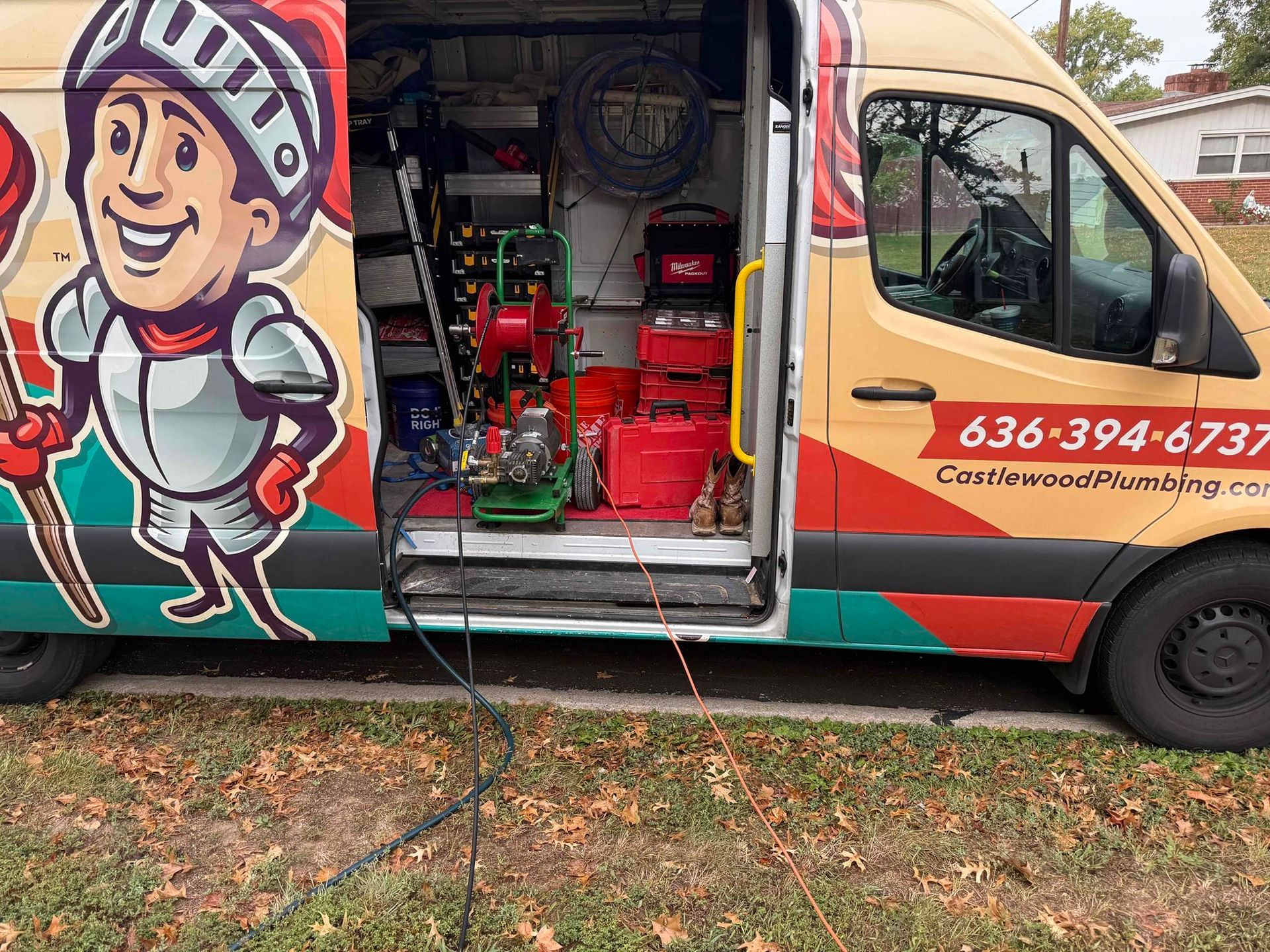 Side view of a colorful van with open side door, showing a red pressure-washing machine inside.