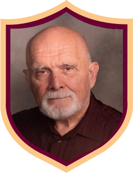 Portrait of an elderly man with a white beard in a maroon shirt, framed by a gold shield border