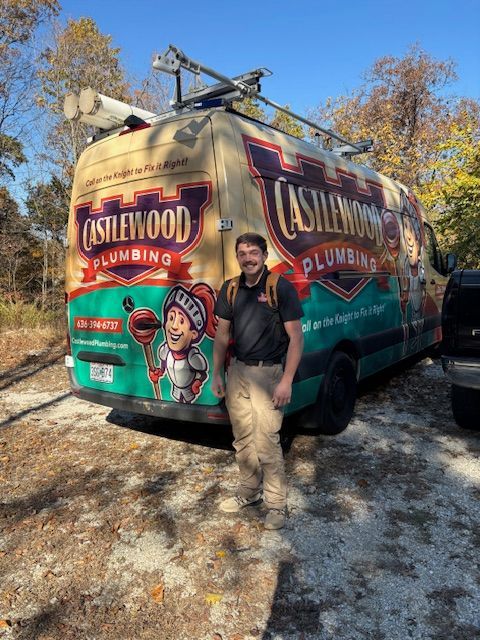 Plumber standing beside a colorful Asplund Plumbing service van on a sunny roadside.