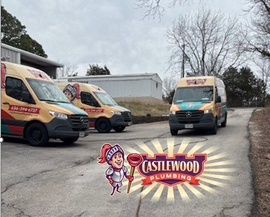 Castlewood Plumbing vans parked on a driveway under a gray sky, with the company logo in front.