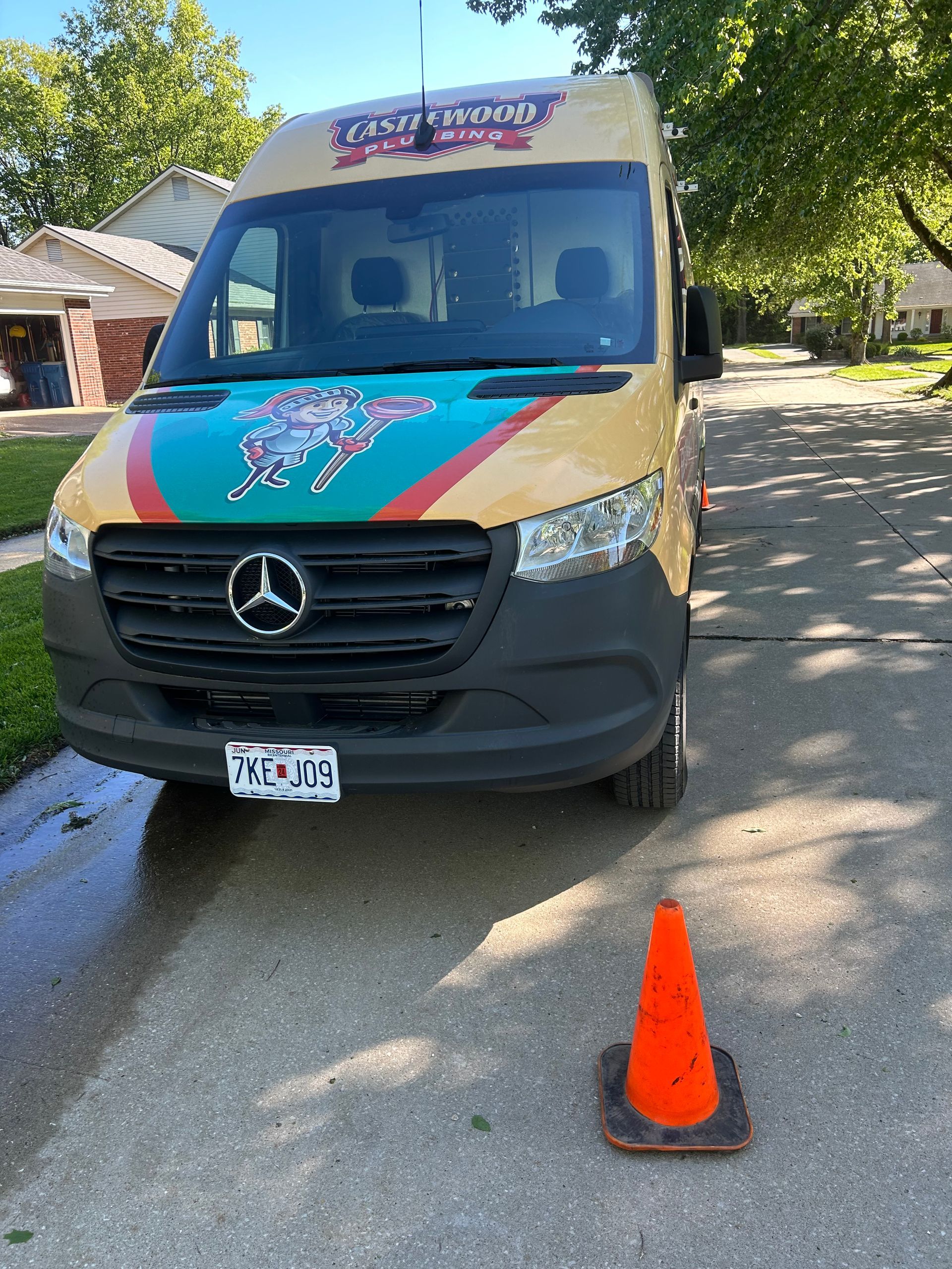 Colorful Mercedes van parked on a street beside an orange traffic cone.