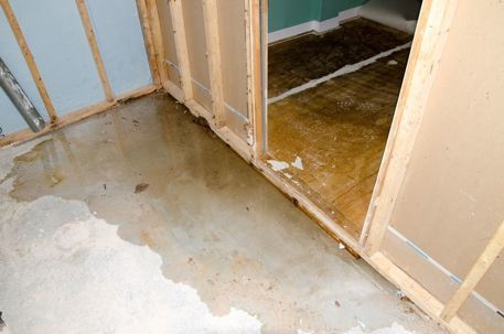 Flooded basement with water on the concrete floor and wooden wall frames.