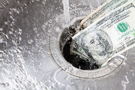 Money being washed down a kitchen sink drain.