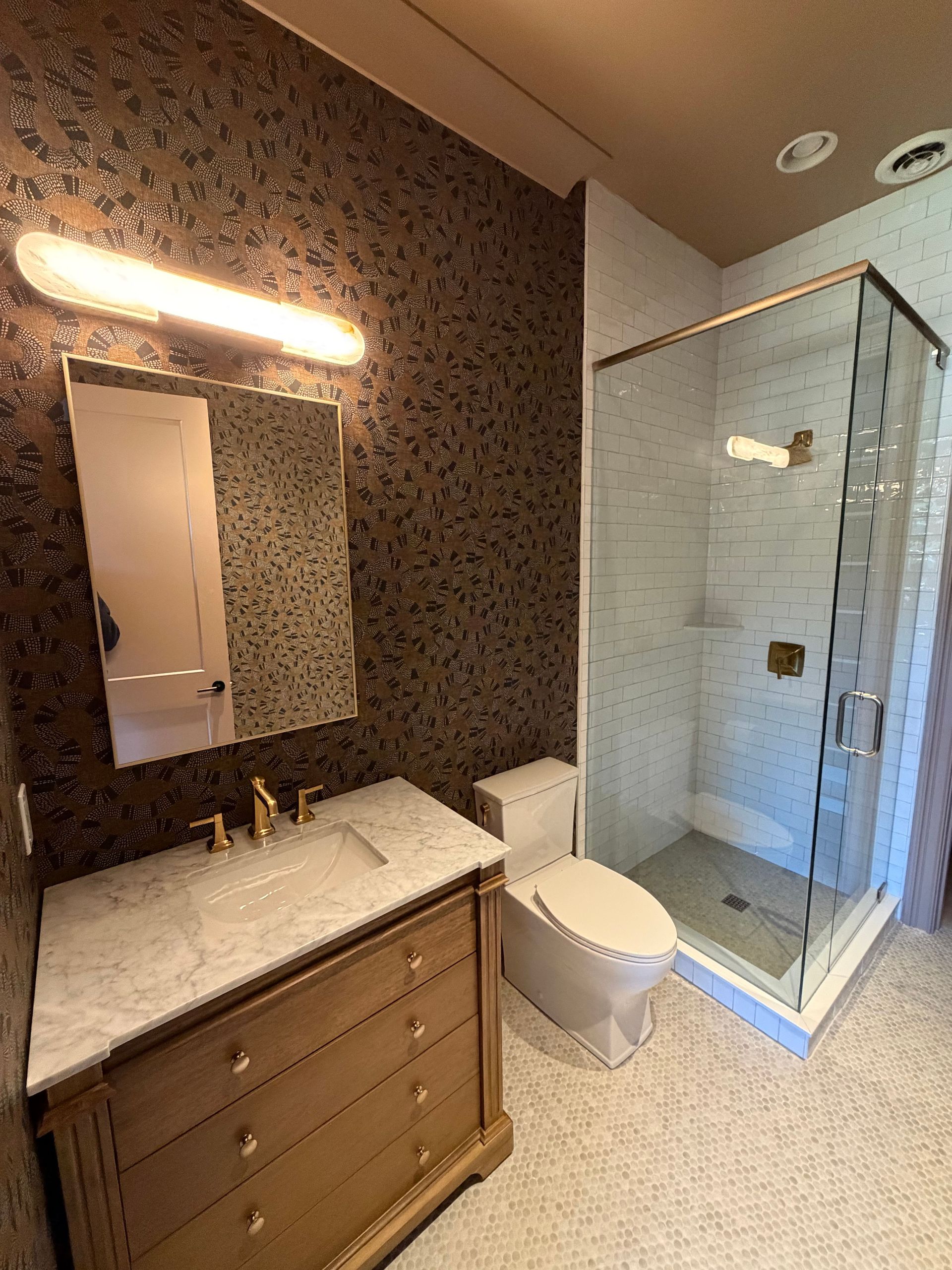 Modern bathroom with marble vanity, illuminated mirror, toilet, and glass-enclosed shower