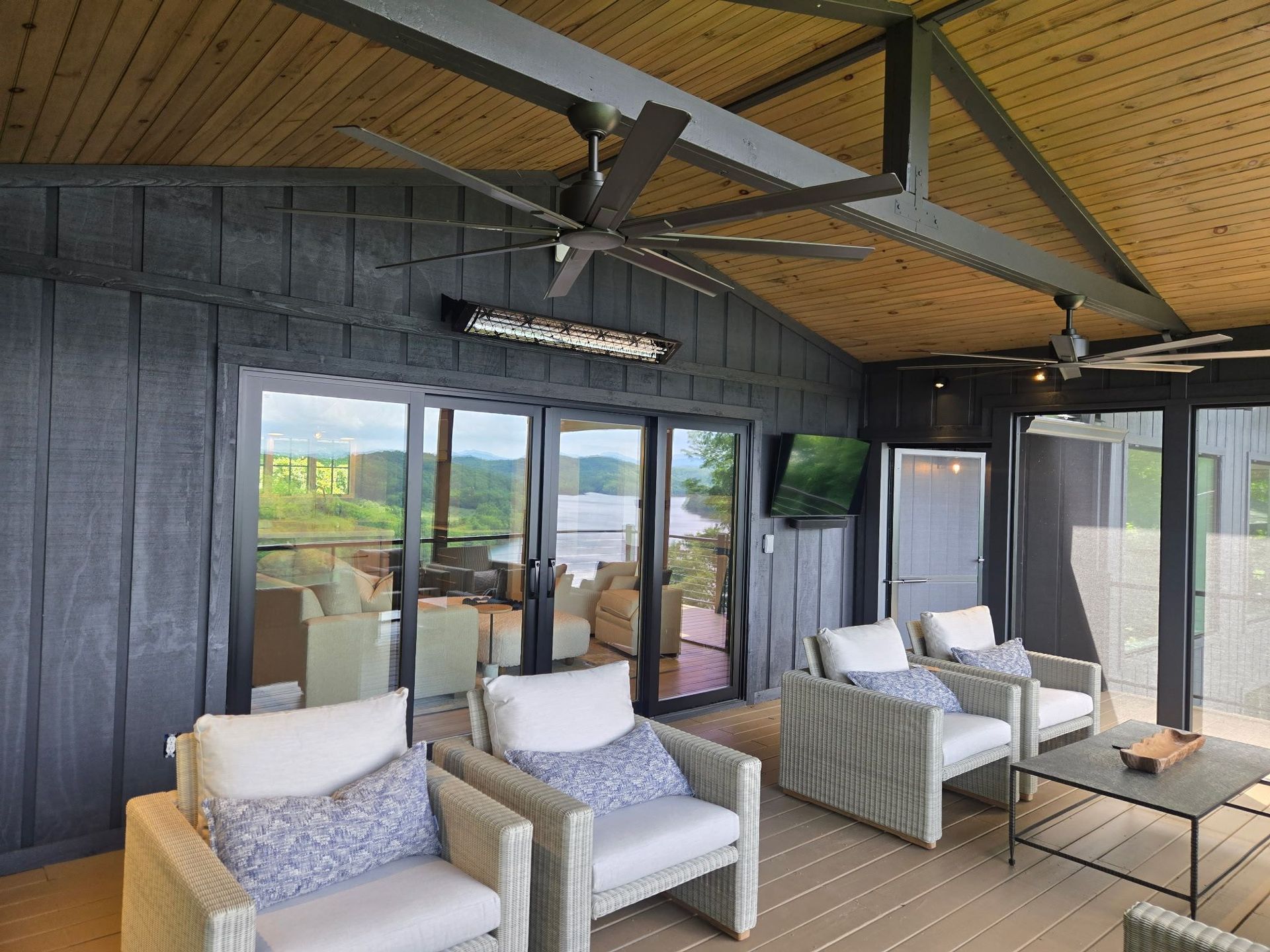 Covered patio seating area with wicker chairs, coffee table, and ceiling fans in front of sliding glass doors