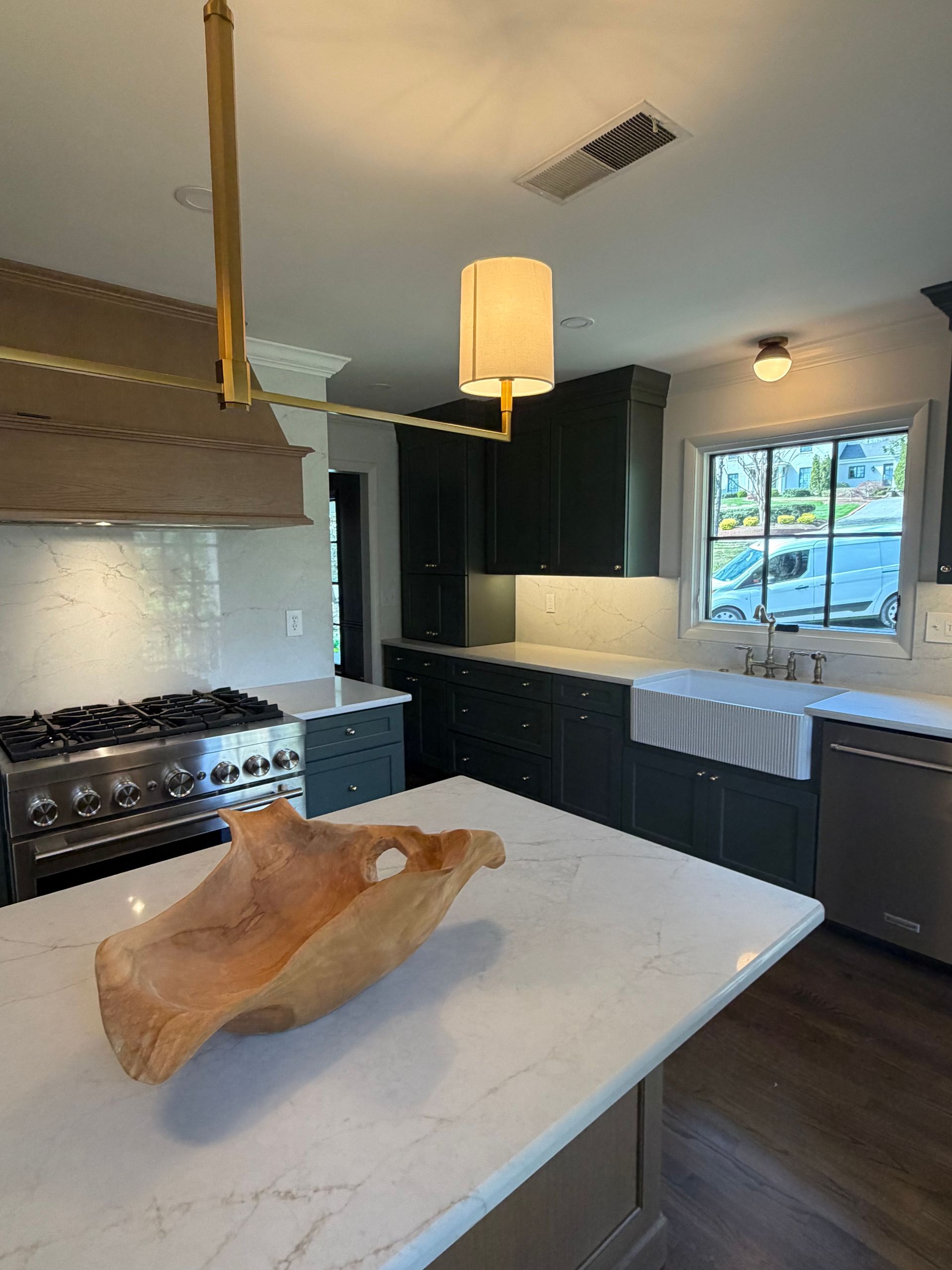Modern kitchen with dark cabinets, large island, gas stove, and window over the sink
