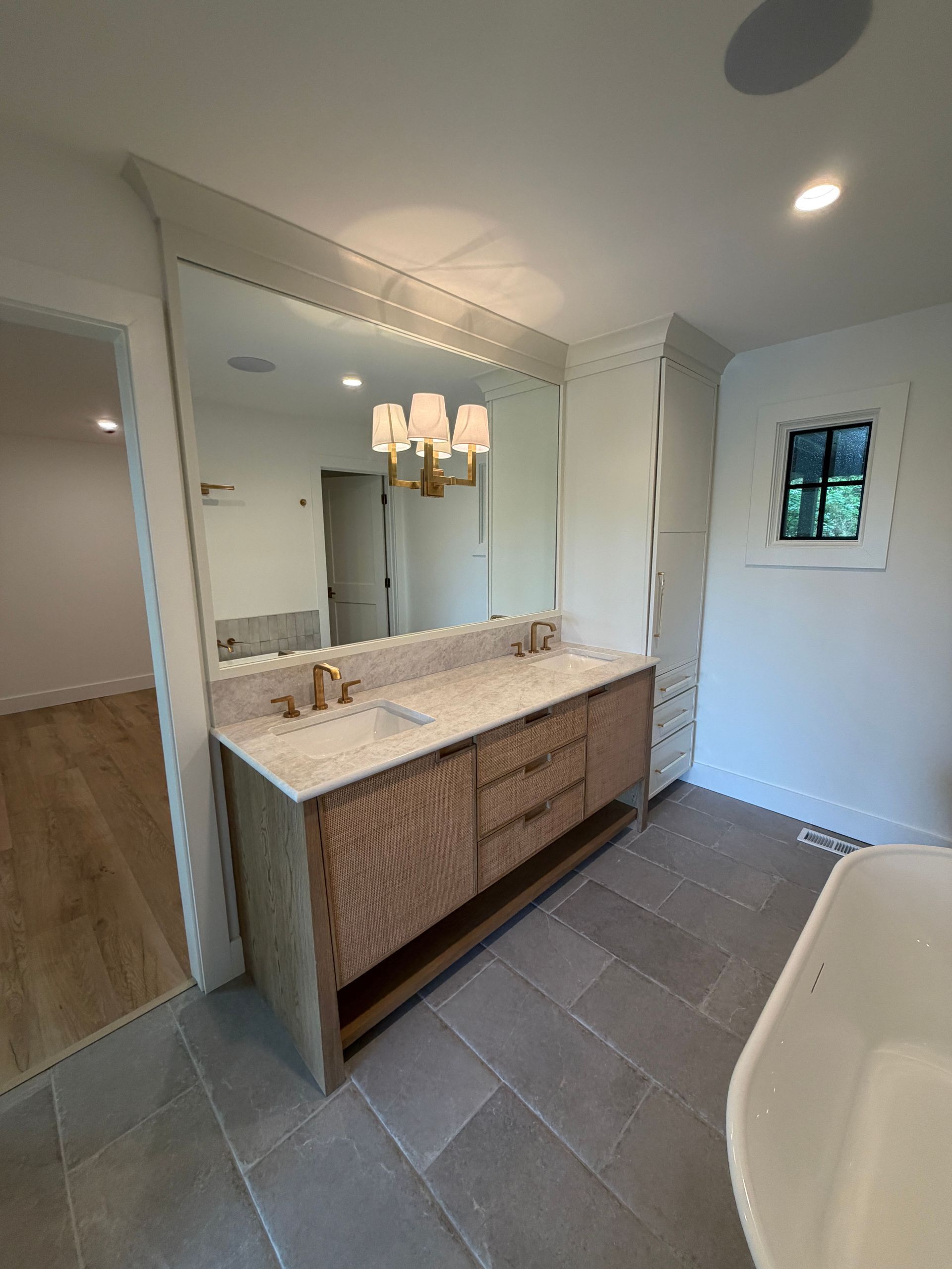 Modern bathroom with double vanity, large mirror, pendant lights, and tiled floor.