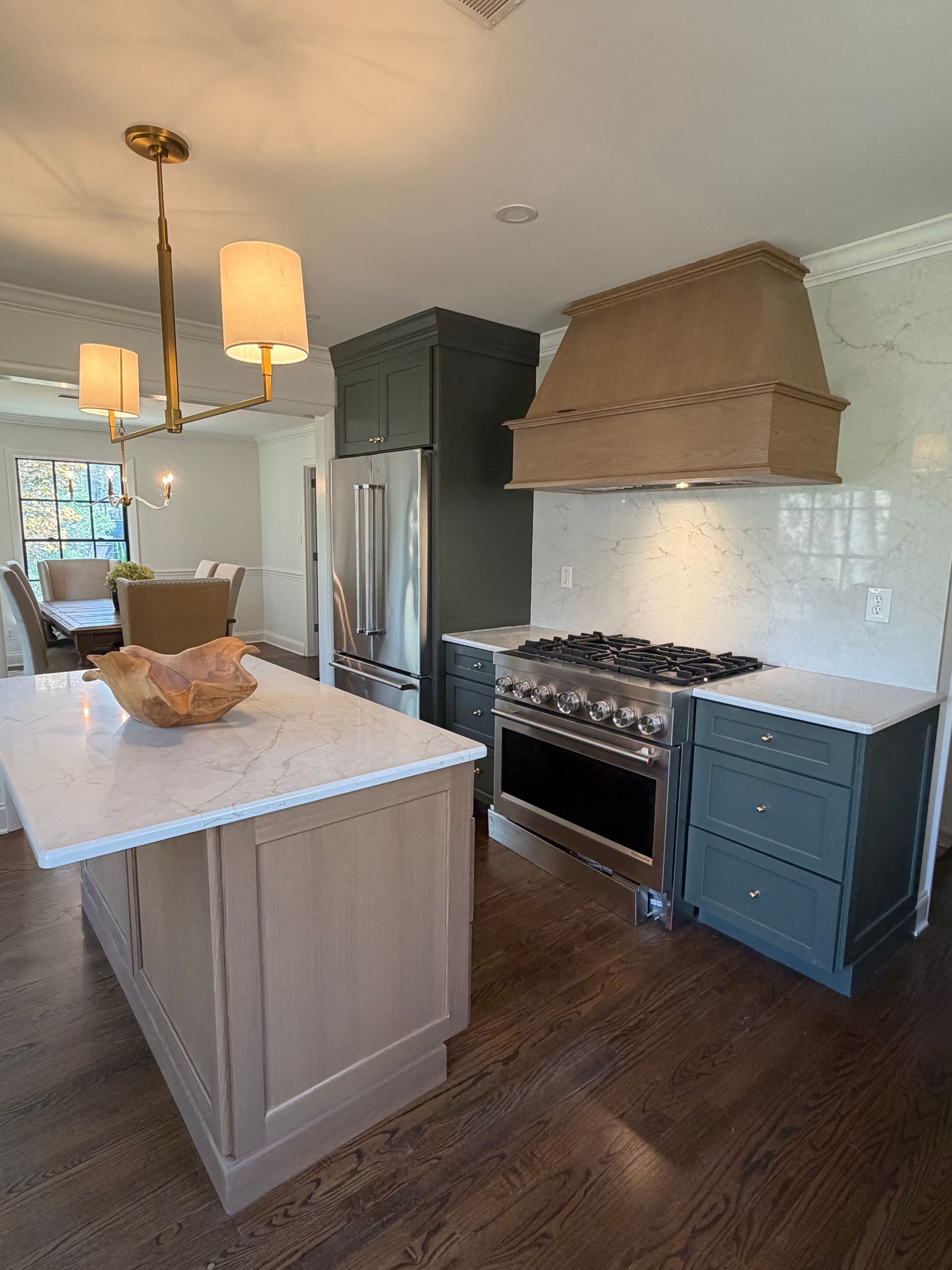 Bright kitchen with white island, dark cabinets, gas range, and wood floors