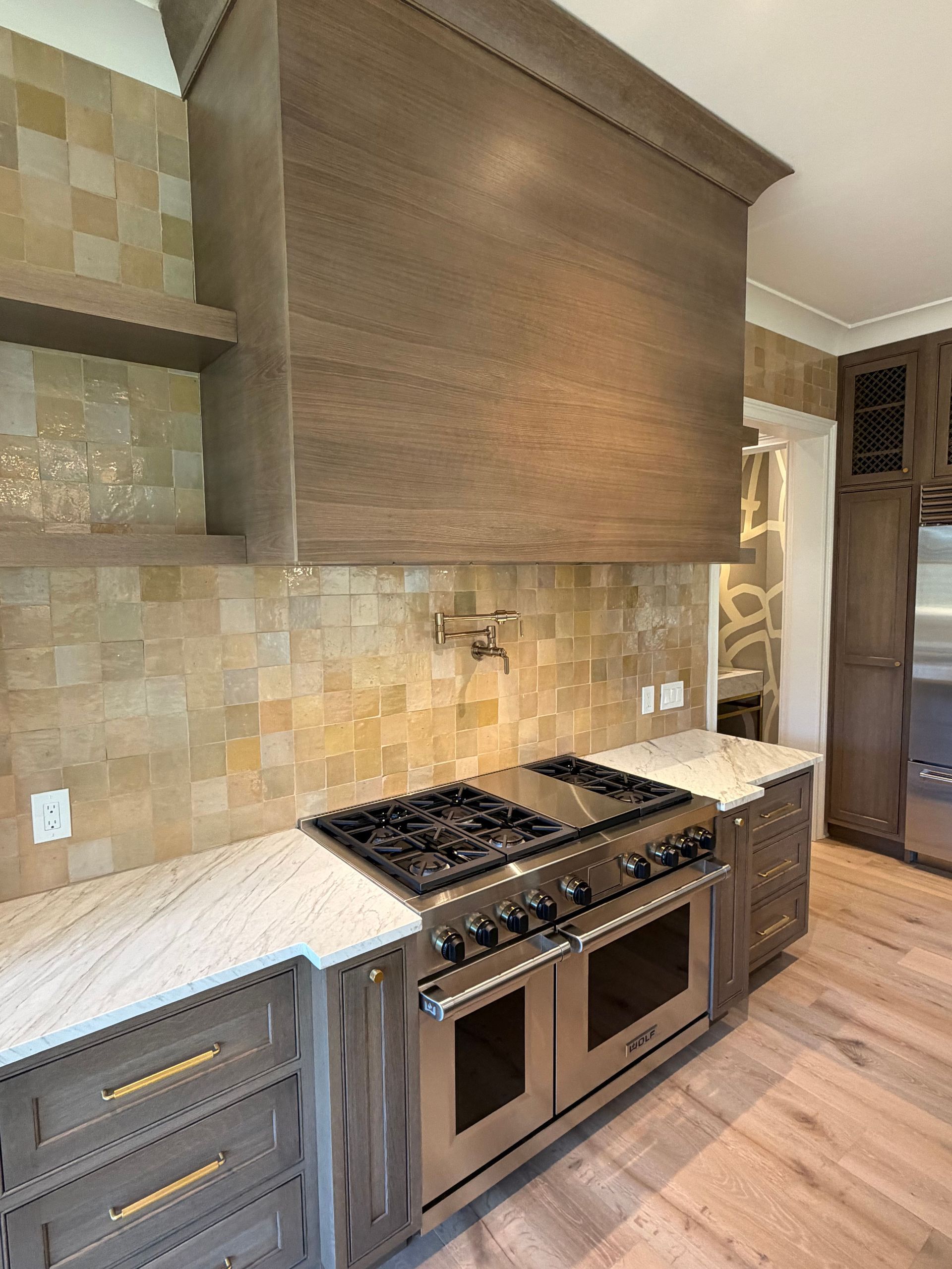 Modern kitchen with stainless steel range, white countertops, beige tile backsplash, and wood cabinetry