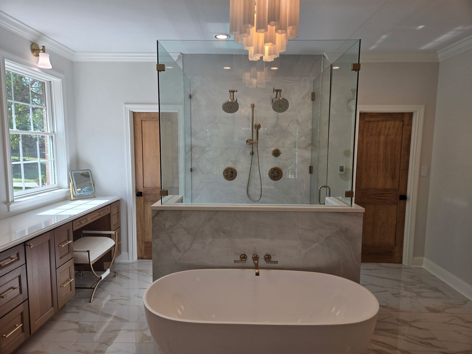 Modern bathroom with freestanding tub, glass shower, wood vanities, and marble tile