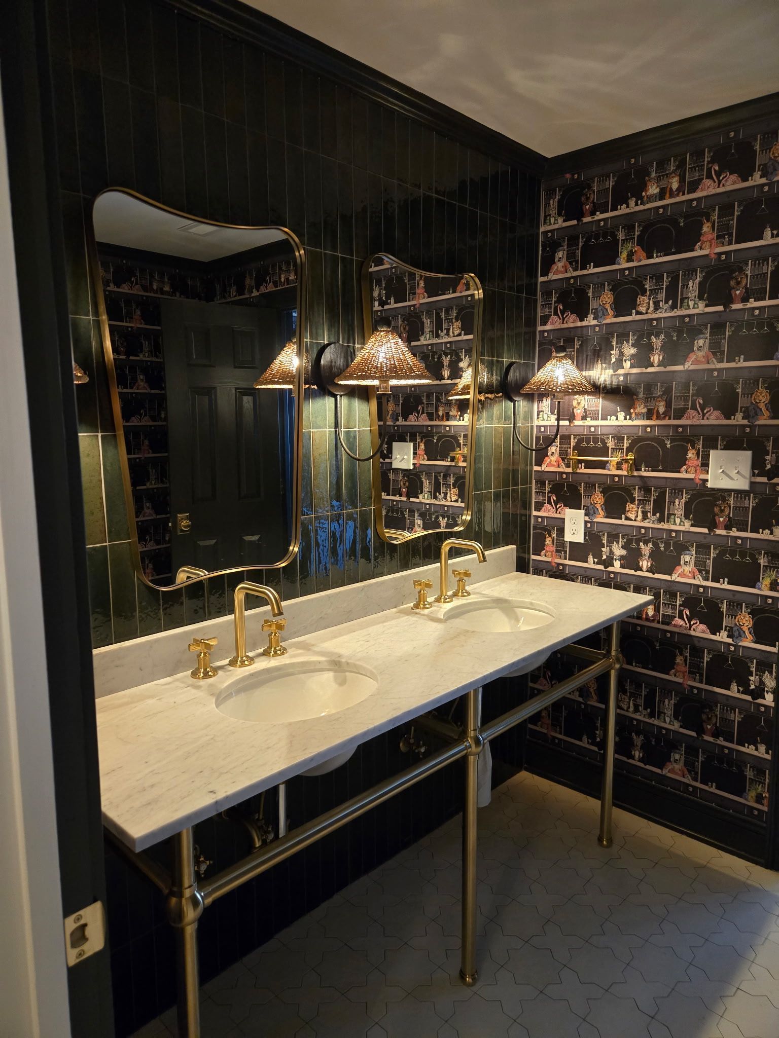 Elegant bathroom vanity with double gold faucets, large mirror, and black floral wallpaper