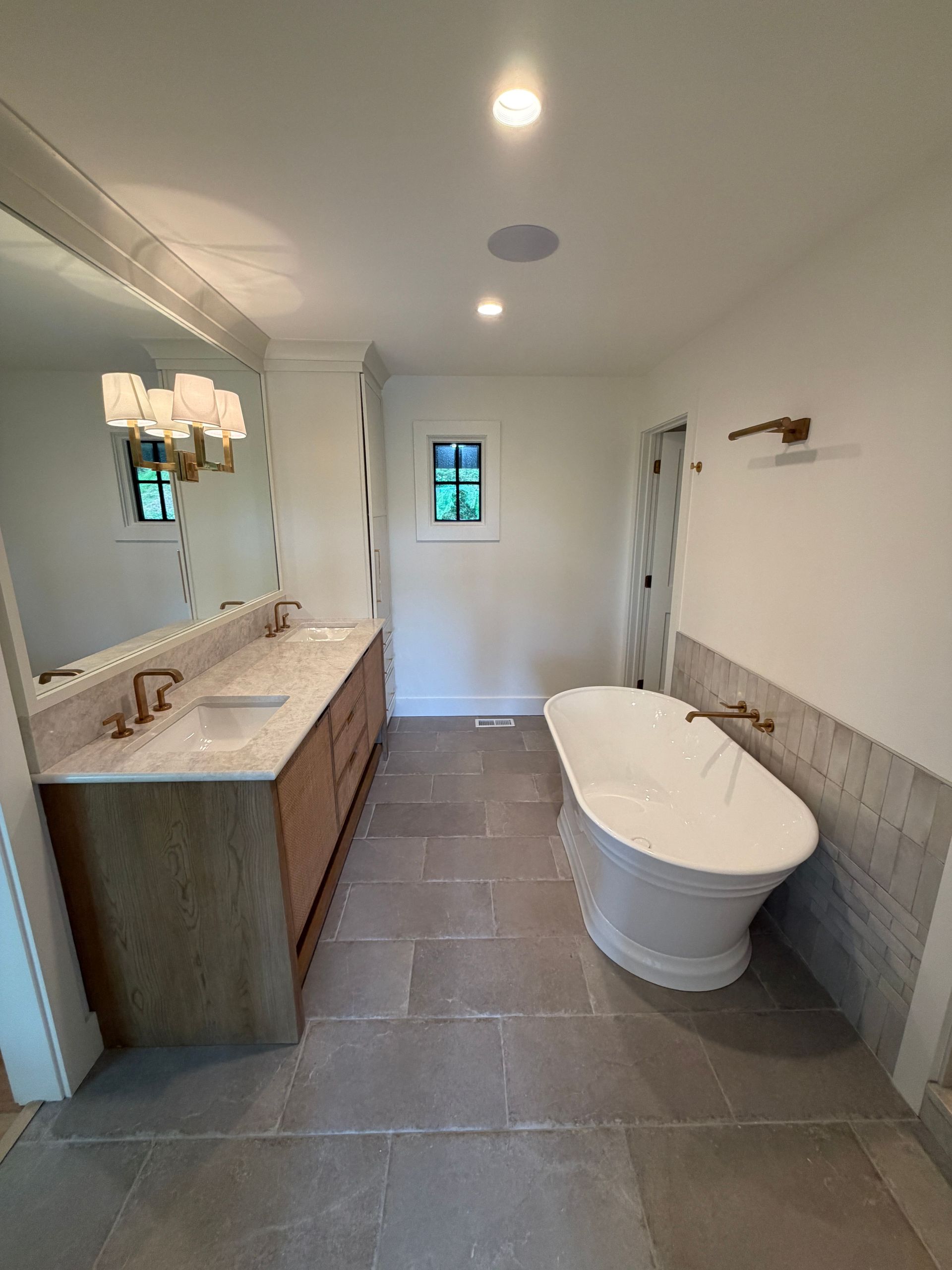Modern bathroom with double vanity, freestanding tub, gray tile floor, and white walls