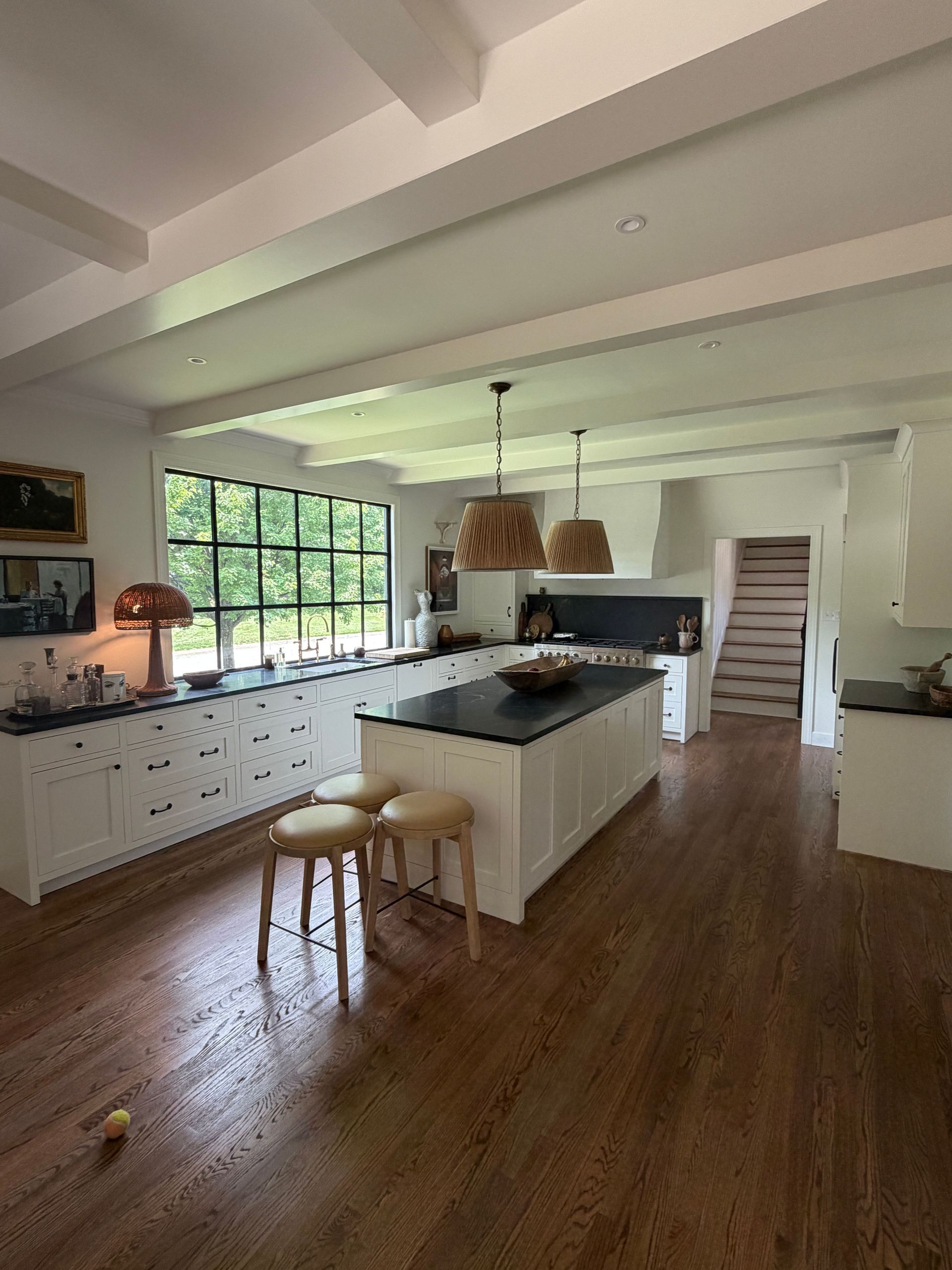 Bright modern kitchen with white cabinets, wood floors, a large island, and a window wall.