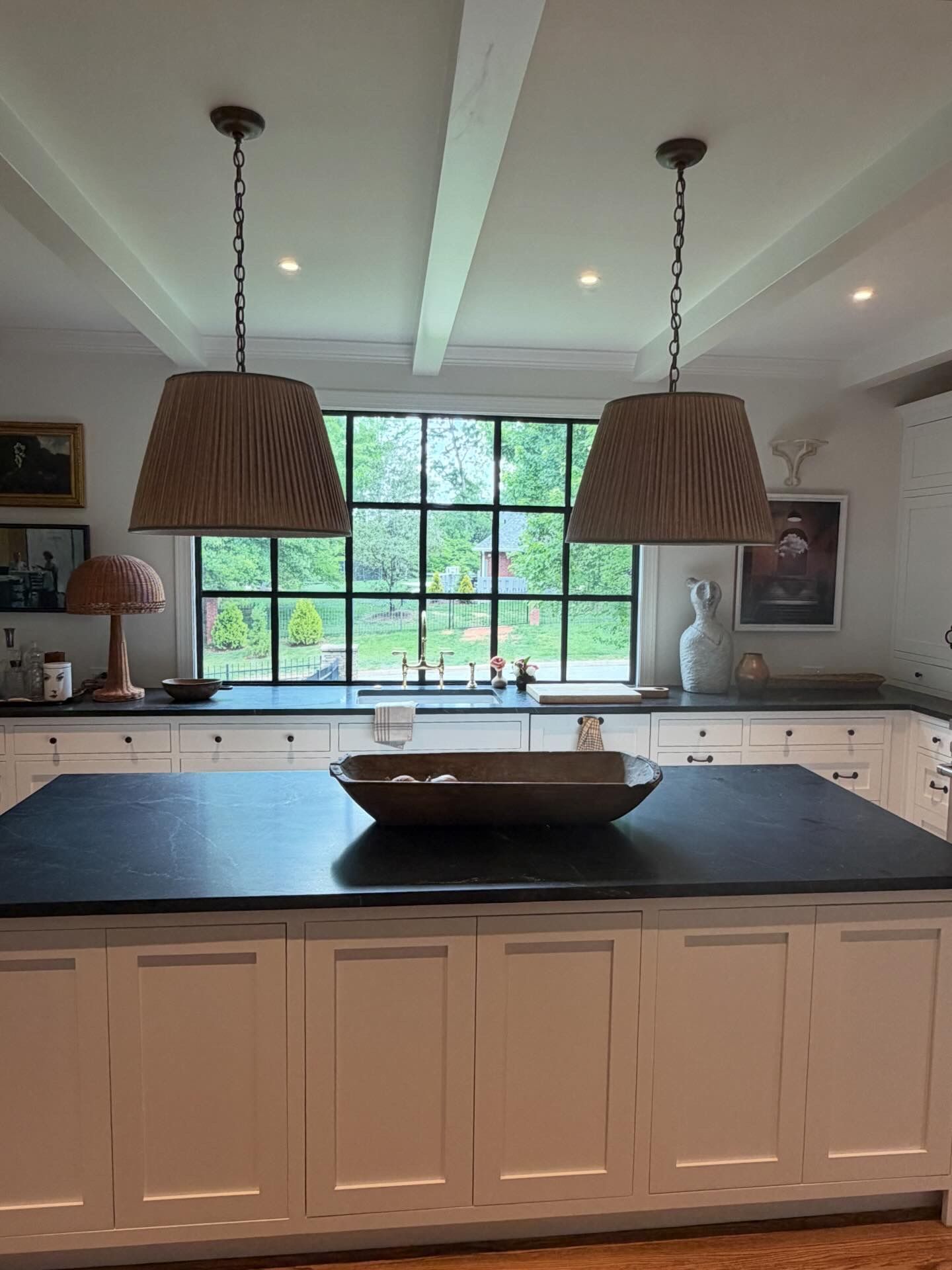 Modern kitchen with large island, black countertop, pendant lights, and window over the sink