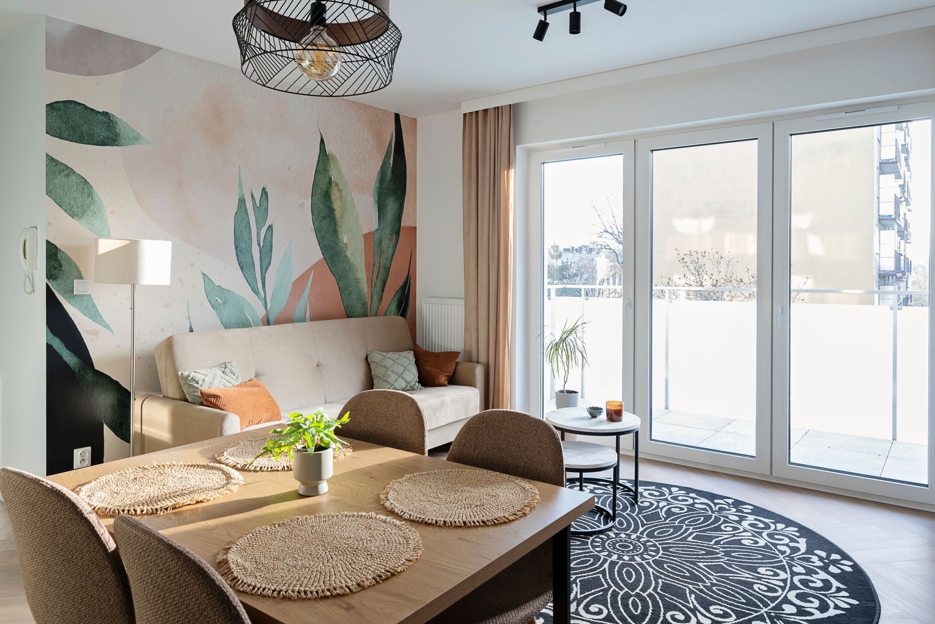 Modern dining nook with floral mural, wooden table, sofa, and sliding glass doors to a snowy balcony