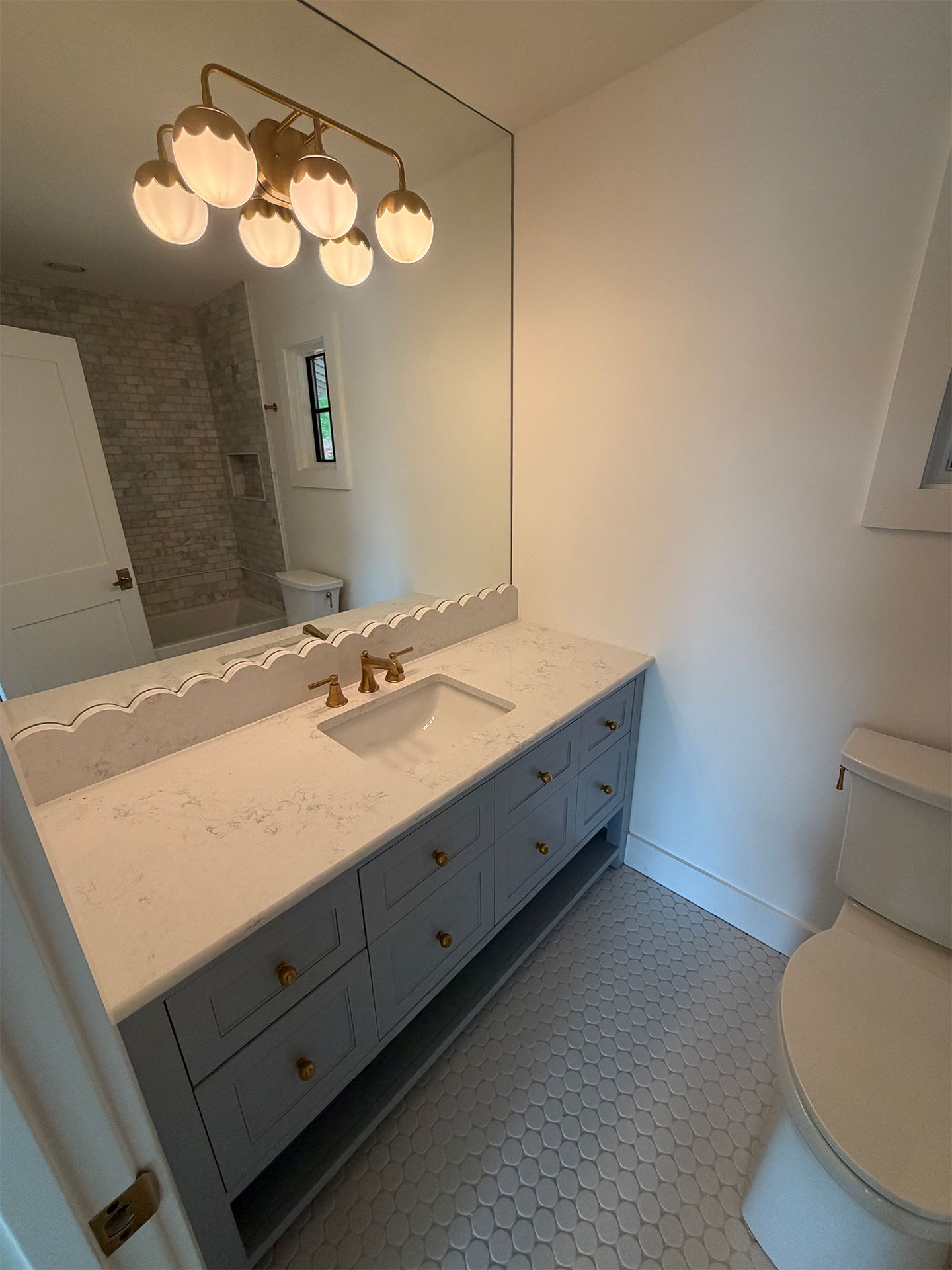 Bathroom vanity with large mirror, blue cabinets, white countertop, and round pendant light fixture