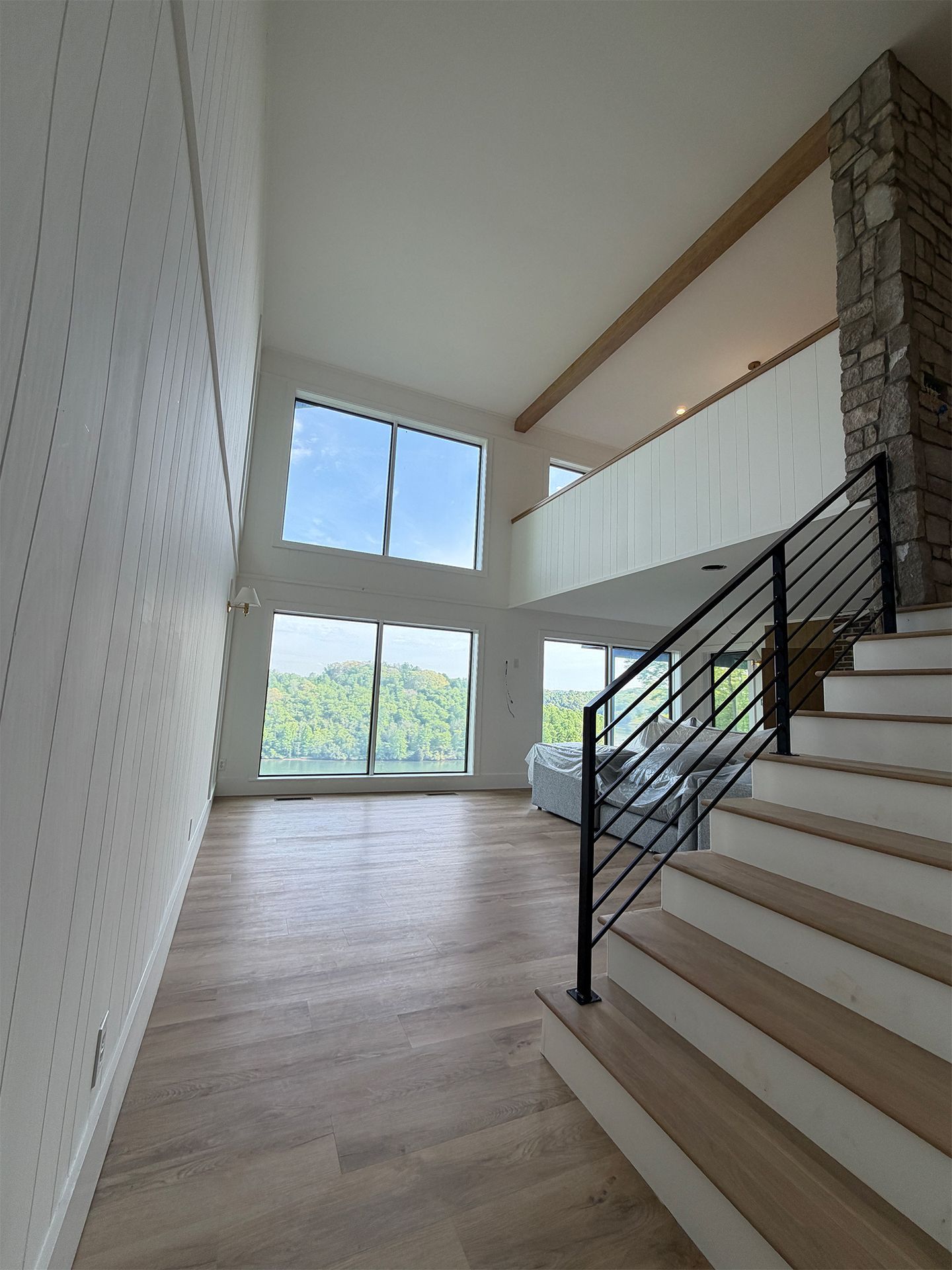Modern stairway in a bright home entry with large windows and stone accent wall