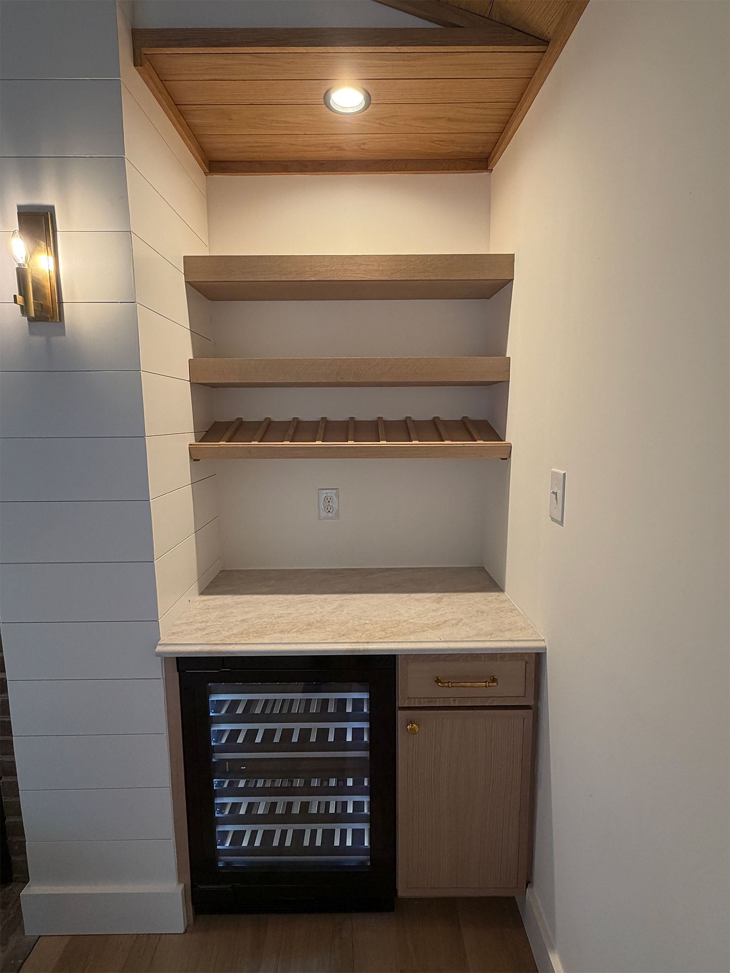 Built-in wet bar with wood shelves, mini fridge, and granite countertop alcove