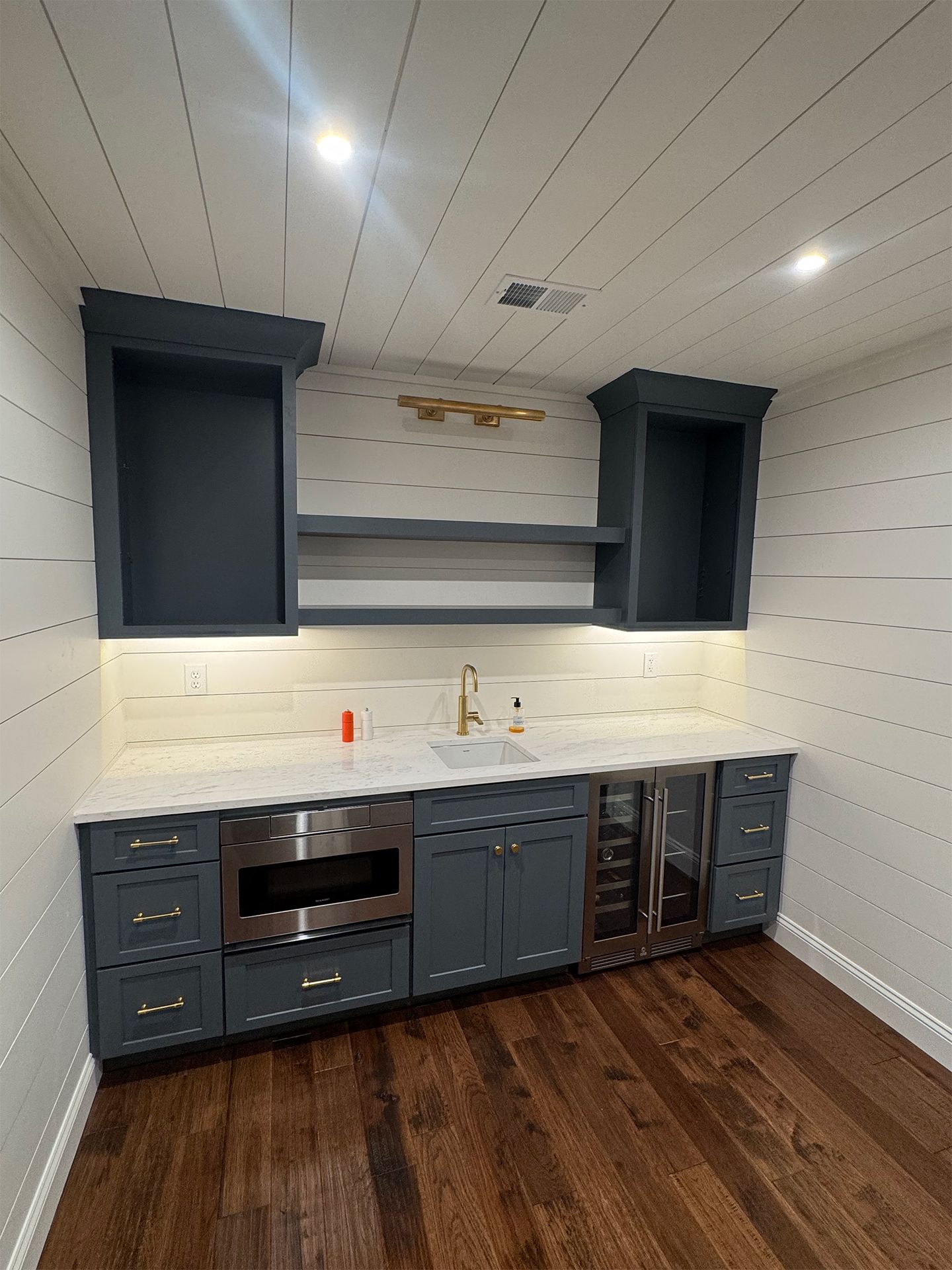 Modern kitchen with navy cabinets, white shiplap walls, and dark wood floors