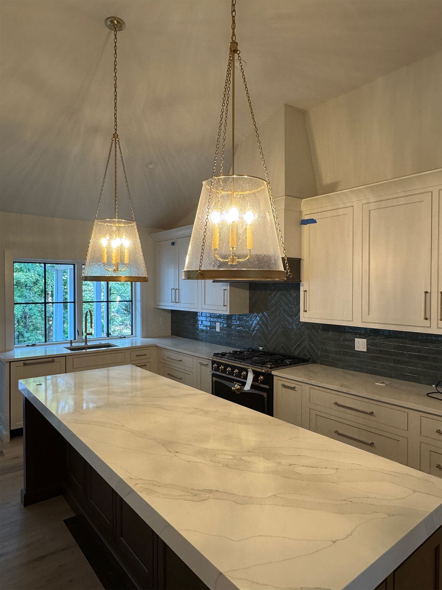 Modern kitchen with large island, pendant lights, white cabinets, and marble-look countertops