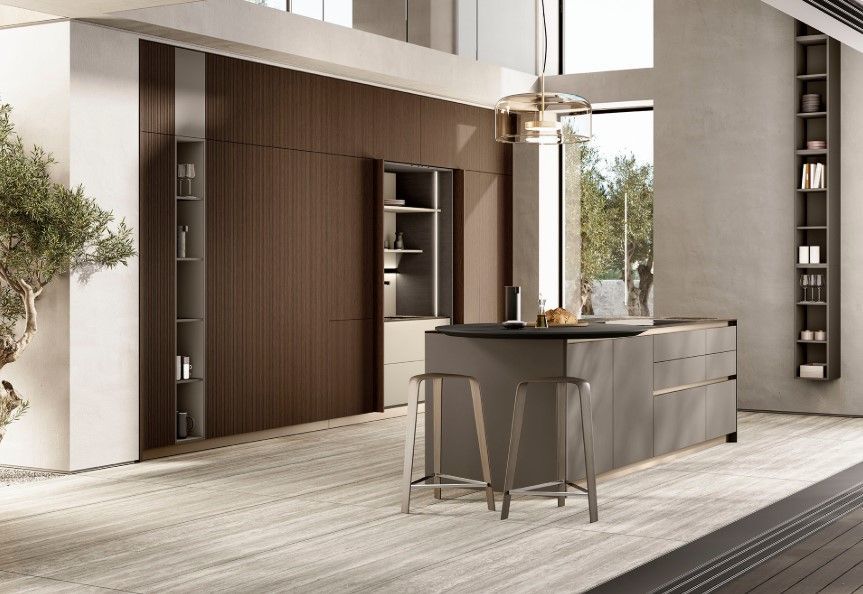 Cucina moderna con mobili in legno, isola grigia e scaffalature alte accanto a una finestra e un albero.