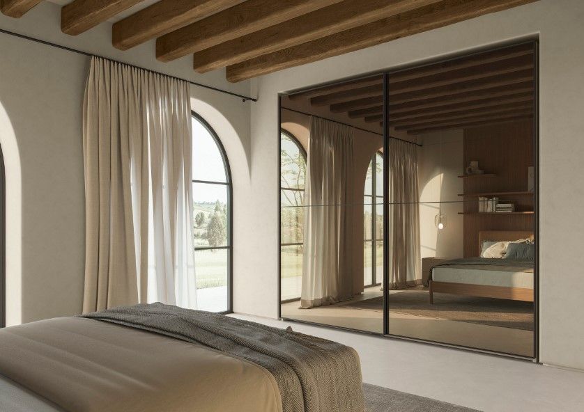 Camera da letto con finestre ad arco, armadio a specchio, travi in legno, toni neutri.