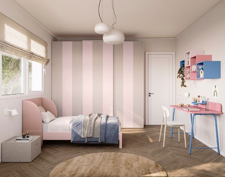 Camera da letto rosa e grigia per bambina, con letto, armadio, scrivania, tappeto rotondo e finestra con tende.