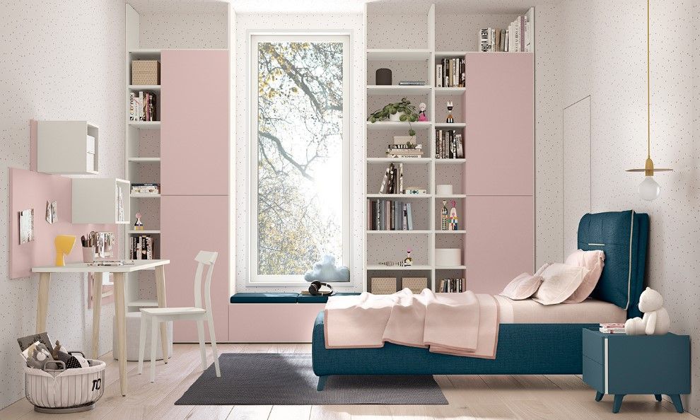 Camera da letto con mobili rosa e verde acqua, scaffali incorporati, scrivania e letto vicino a una finestra.