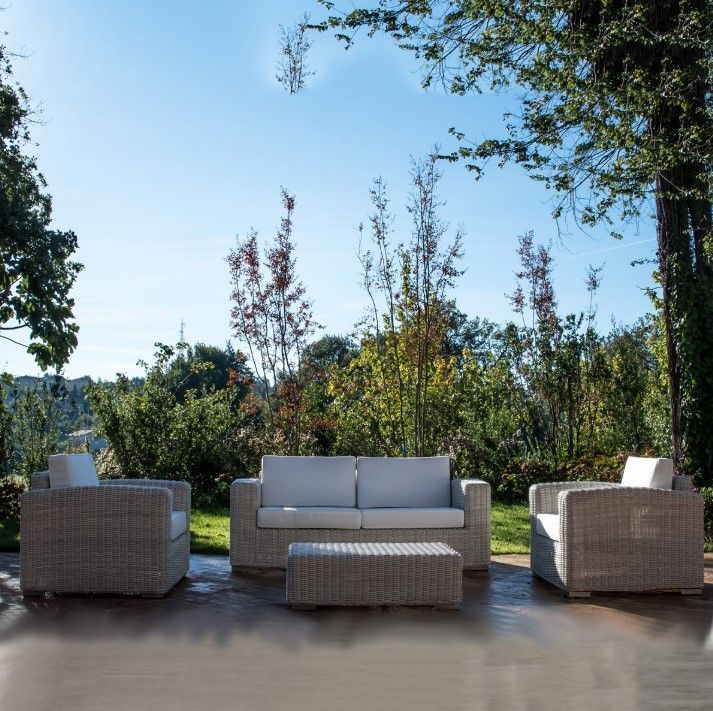 Arredamento da esterno per patio in una giornata di sole. Divano, sedie e pouf in vimini chiaro.