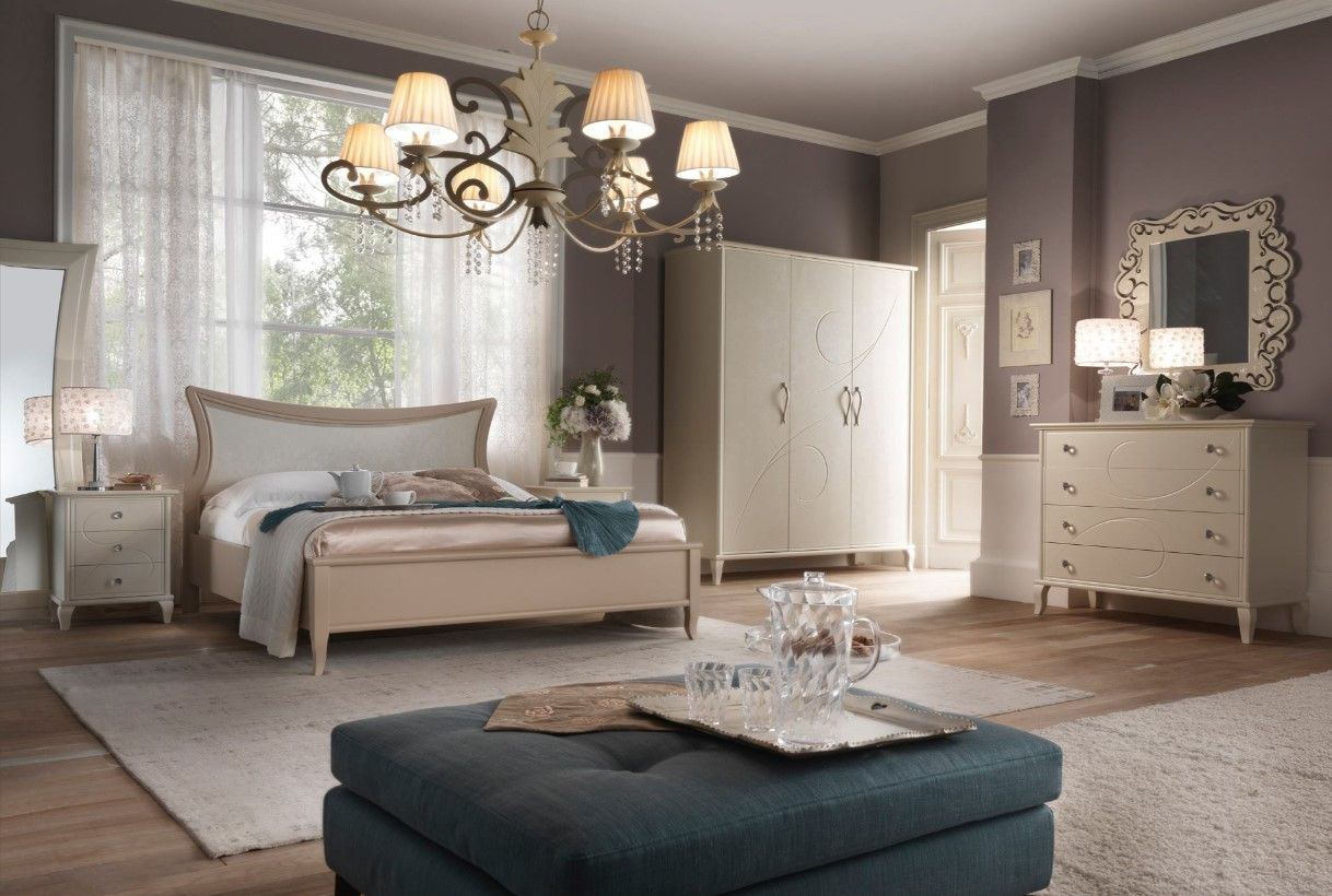 Elegante camera da letto con mobili dai colori chiari, lampadario e pareti viola.