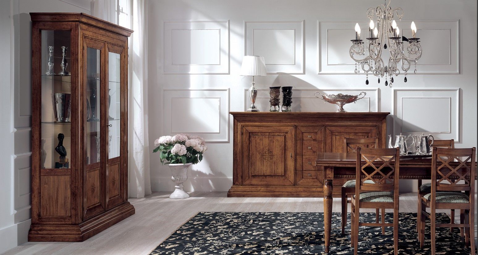 Sala da pranzo con mobili in legno, tra cui una vetrina, una credenza, un tavolo e sedie. Lampadario e tappeto.