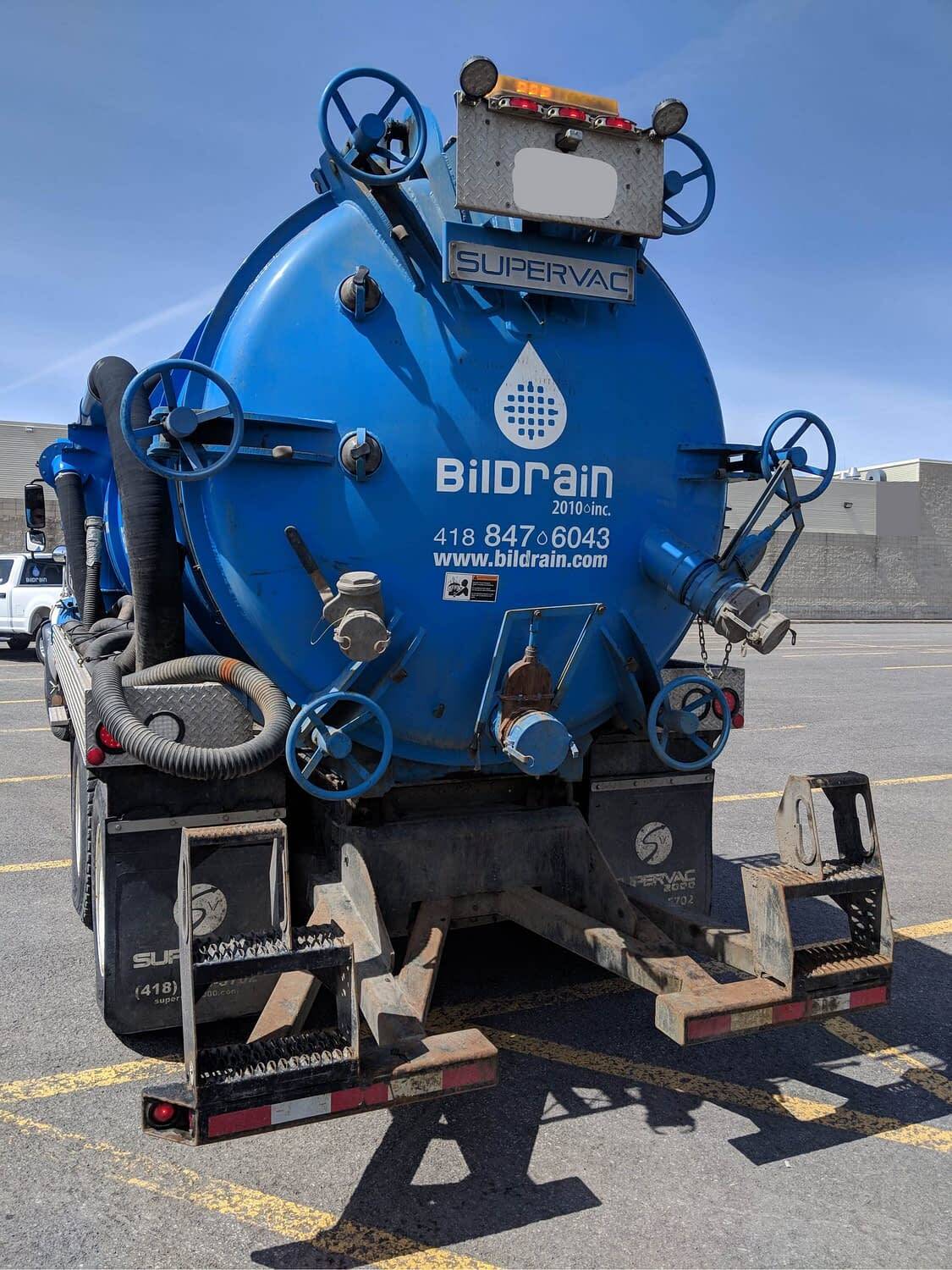 Un camion aspirateur bleu est garé sur un parking.
