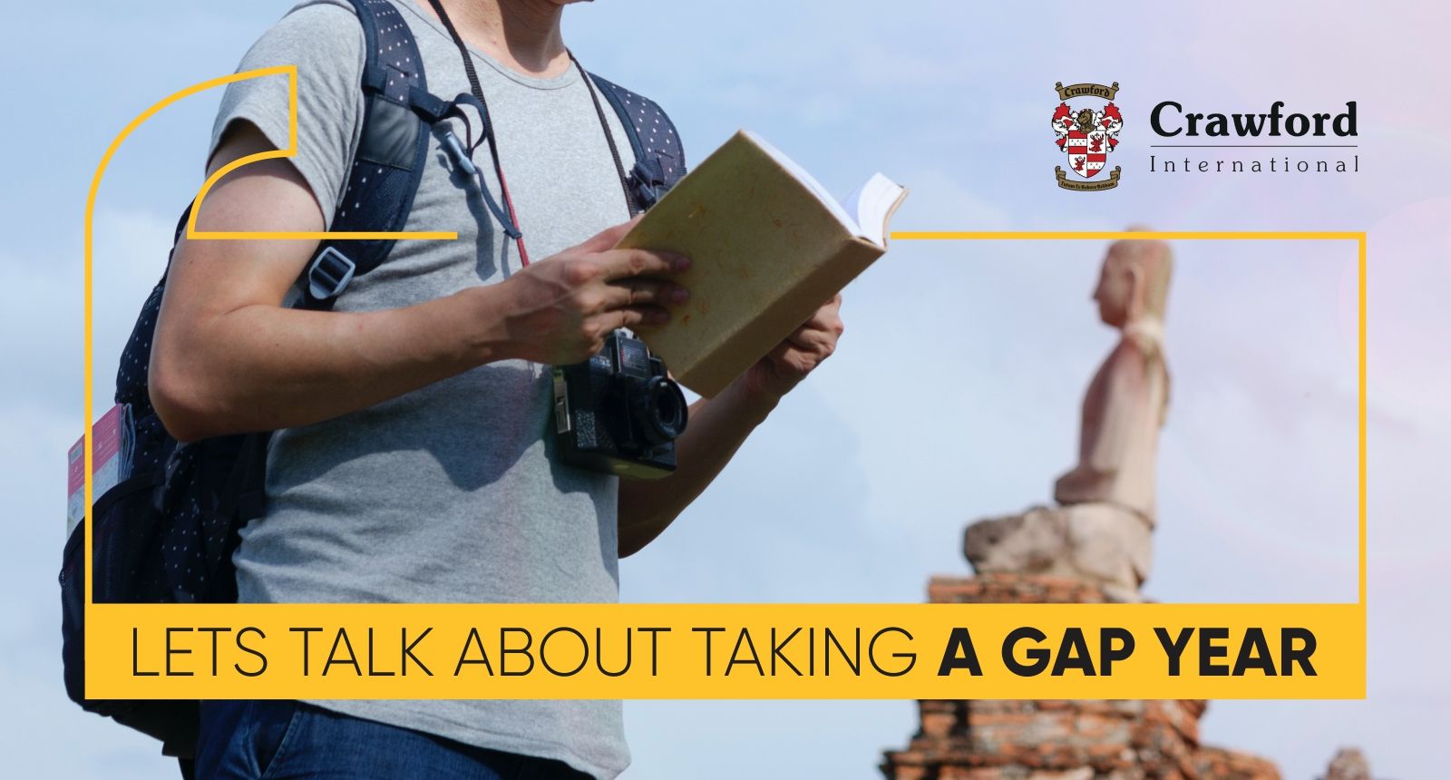 A man with a backpack is reading a book in front of a statue.