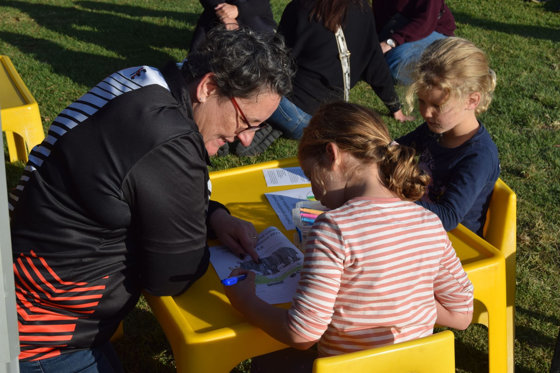 A woman is sitting at a table with two little girls.