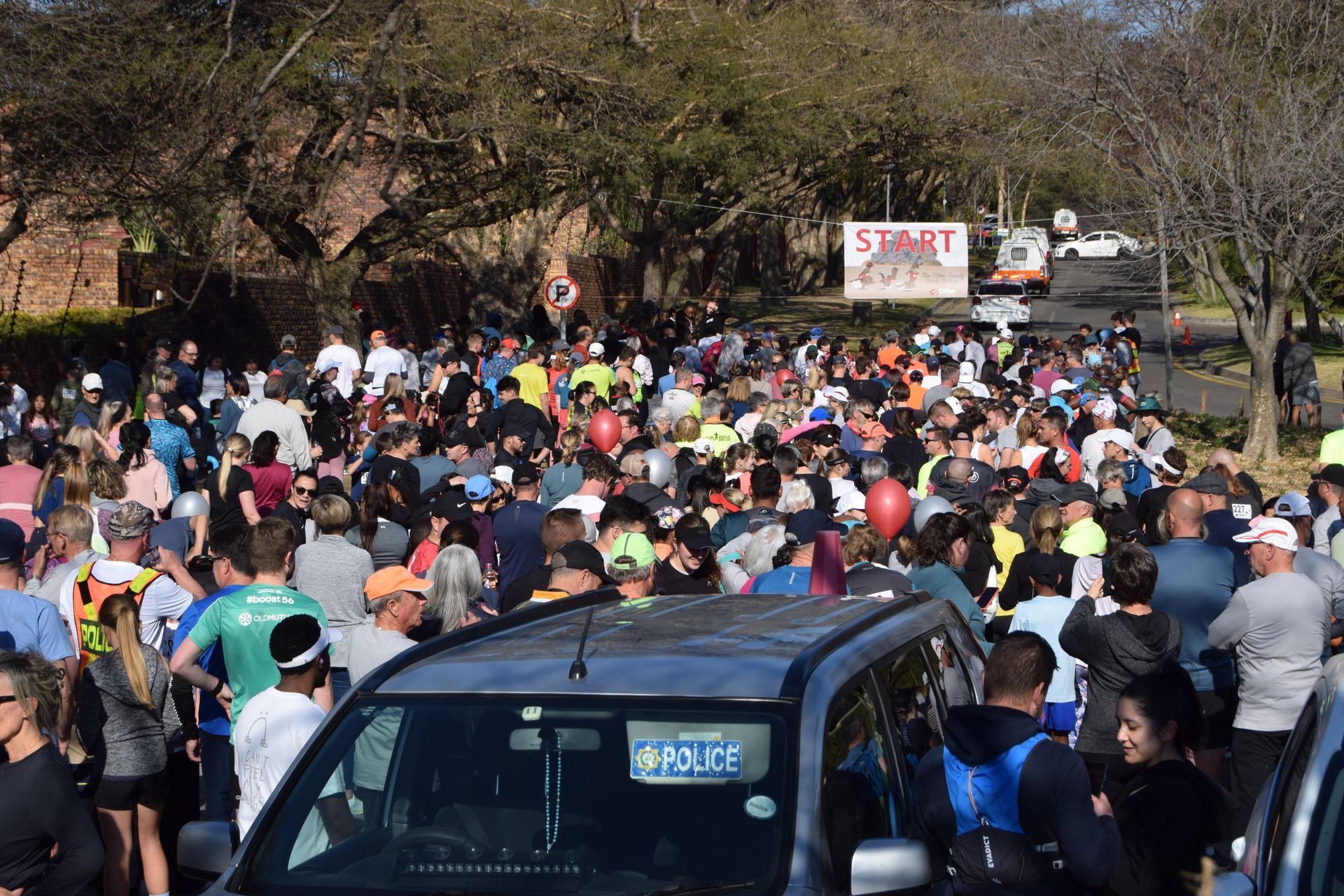 A large crowd of people are gathered around a car.