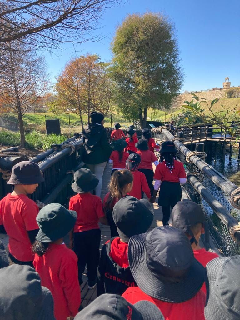 A group of children are walking across a bridge in a park.