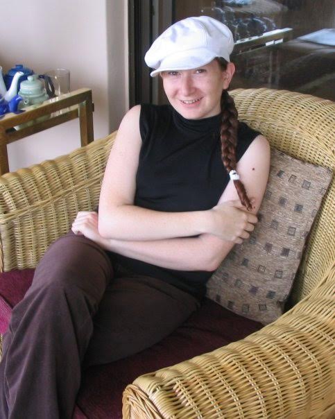 A woman wearing a white hat is sitting in a wicker chair